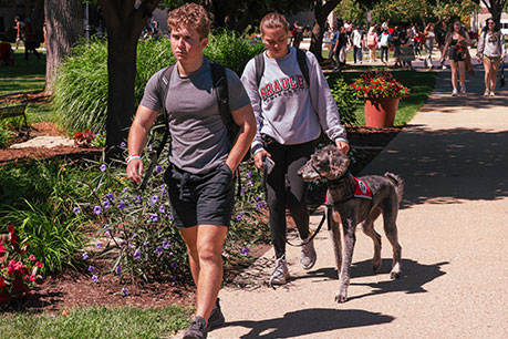 Students walking with a service dog. Links to Gifts by Will